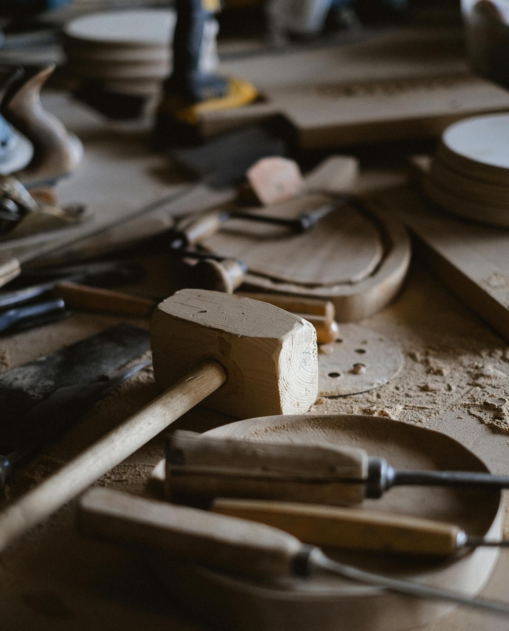 A variety of woodworking tools scattered on a workbench in a workshop setting.