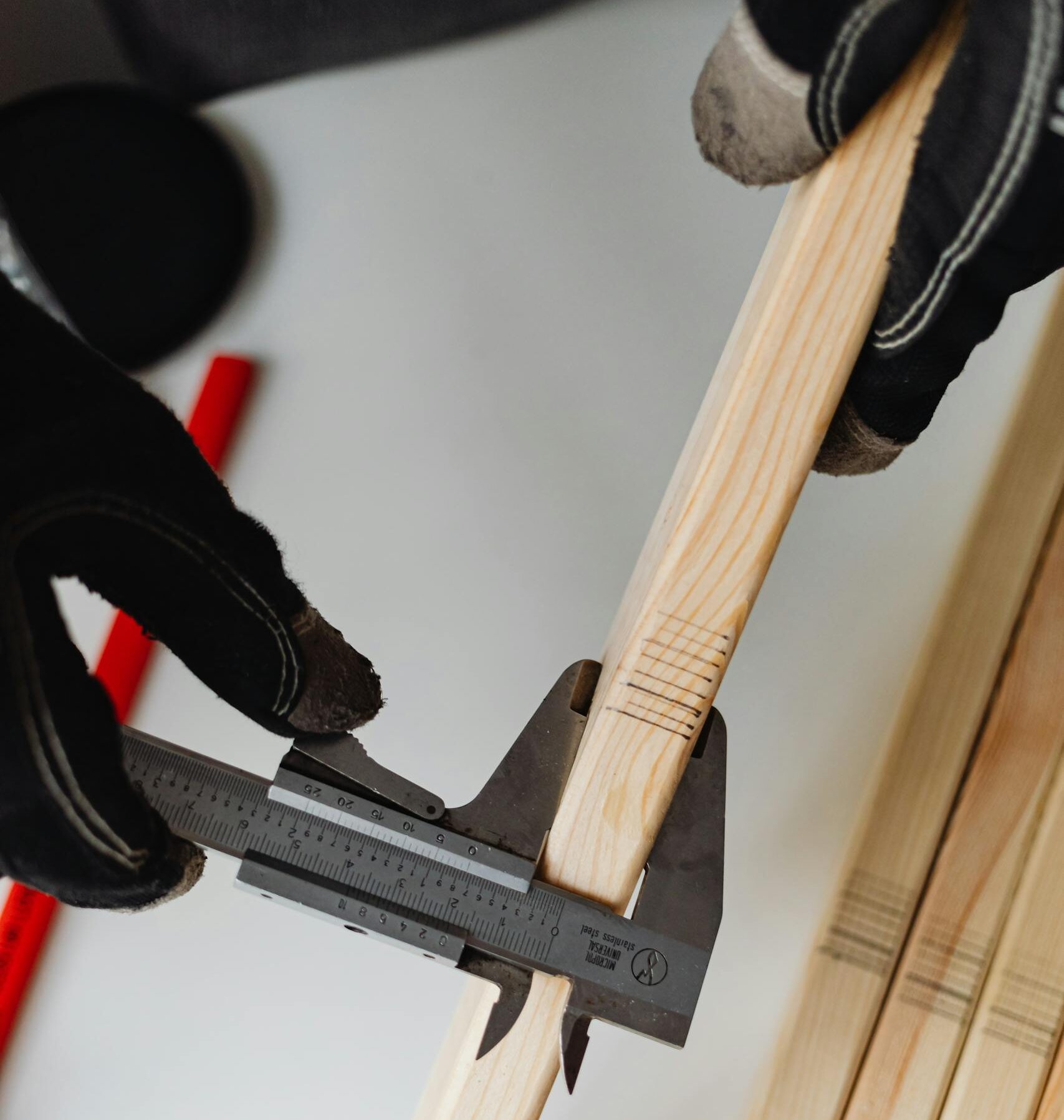 Close-up of a carpenter using a caliper on woodwork, highlighting precision tools.