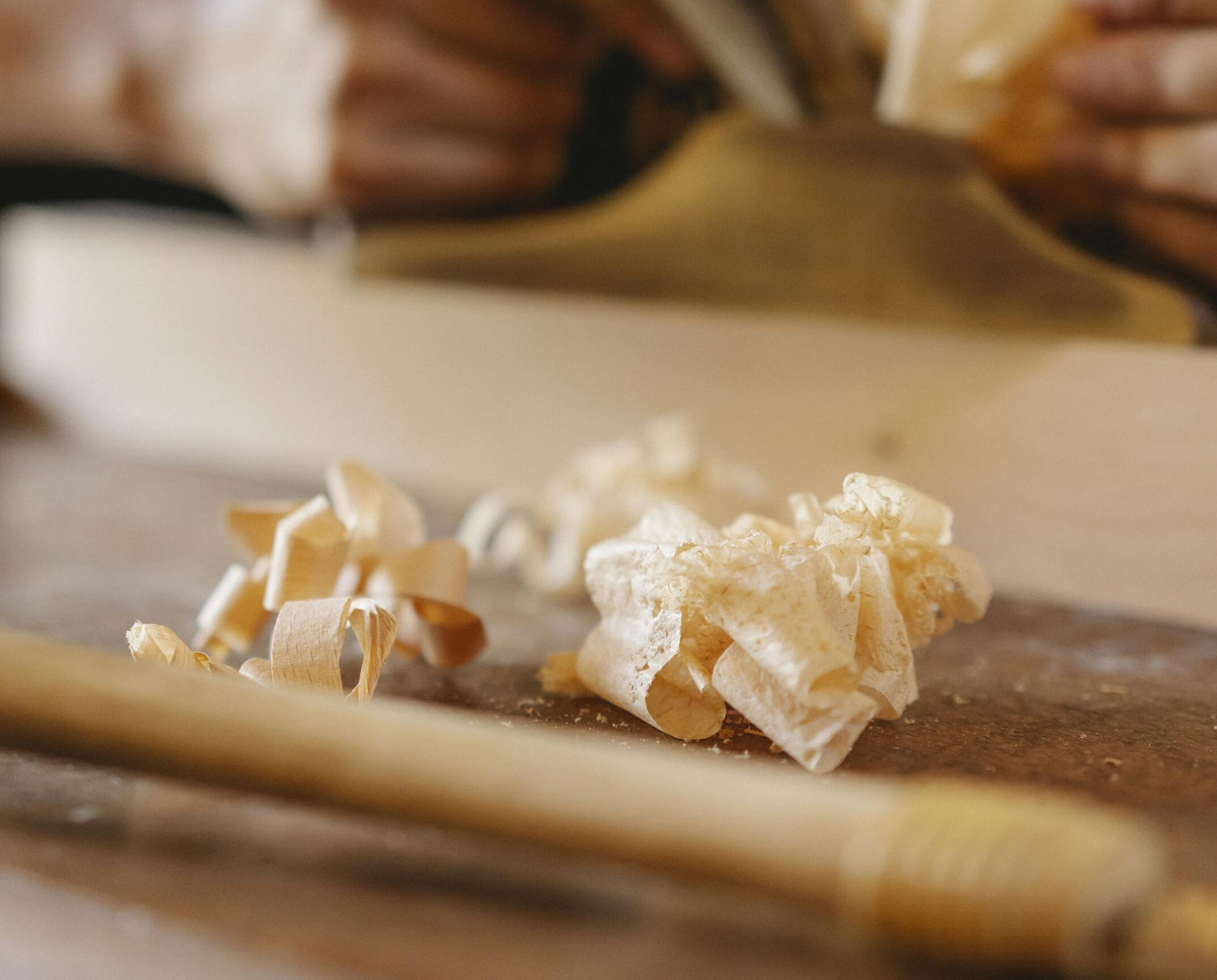 Detailed view of wood shavings and carpentry tools showcasing craftsmanship in a workshop setting.